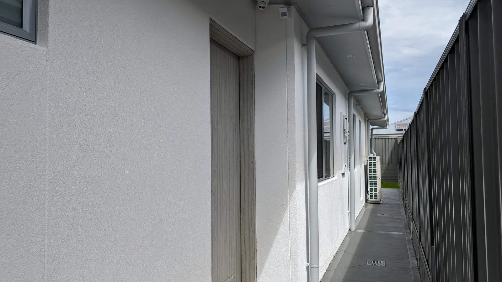 Side access beside a rendered Hebel home with eaves, gutters, downpipes and path drainage.