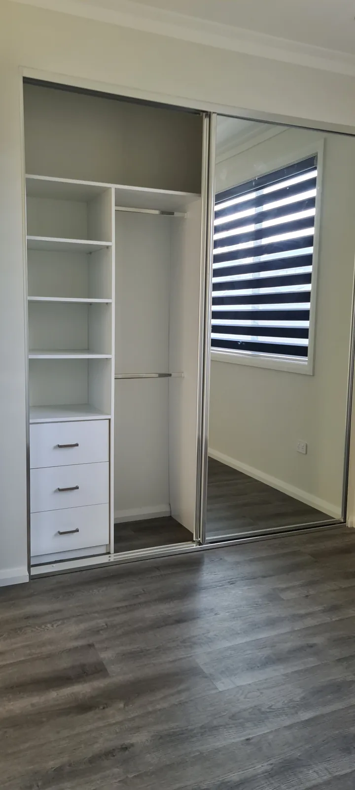 Open fitted wardrobe with shelves, three drawers, two hanging rails and a sliding mirrored door.